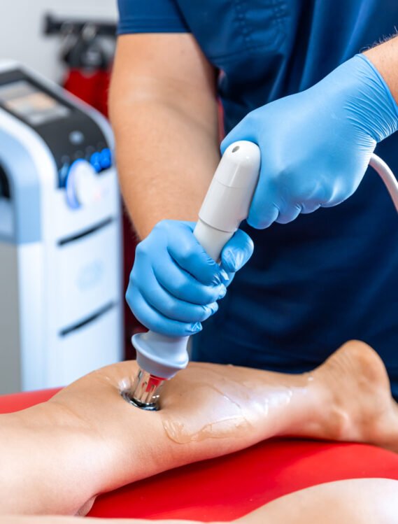 Physical therapy of the shin with shock wave, extracorporeal shockwave therapy. Shock wave therapy, the magnetic field, rehabilitation, physiotherapist doctor performs surgery on a patient's shin.
