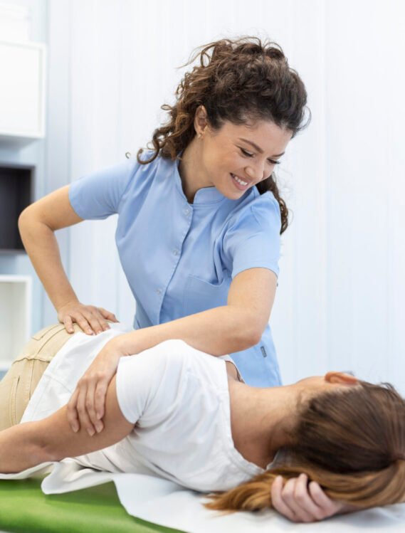 Young woman doctor chiropractor or osteopath fixing lying womans back with hands movements during visit in manual therapy clinic. Professional chiropractor during work
